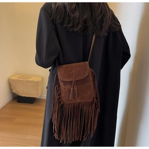 Vue détaillée du sac bandoulière bohème en daim marron avec franges sur un manteau noir