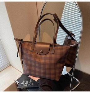 Close-up of brown plaid tote bag showing leather strap and secure zipper closure