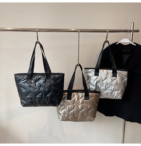 Three quilted puffer tote bags in black, gold and silver finishes hanging on hangers