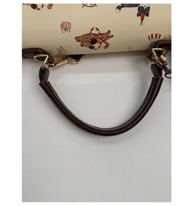 Détail de la poignée en cuir marron avec boucle dorée et motifs de chiens illustrés