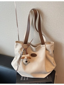 Minimalist beige canvas tote bag with brown leather handles and cute plush dog pendant