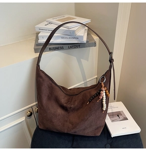 Detail of suede crossbody bag with vintage wooden and ceramic bead tassel decoration