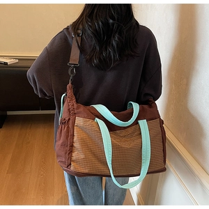 Large canvas tote bag with brown plaid pocket and mint green handles shown worn as a crossbody