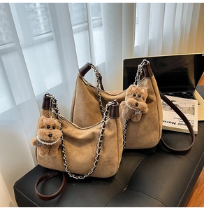 Detail of two brown suede hobo bags with metal chain straps and plush bear charms