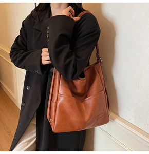 Close-up of a vintage caramel brown tote bag featuring a front pocket and leather strap