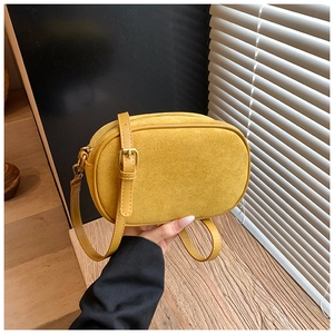 Detail of a mustard yellow frosted crossbody bag with adjustable leather strap in natural light