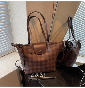 Detail of checkered tote bag featuring a leather flap closure and snap button design