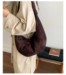 Detail of dark brown suede crossbody bag with diagonal stitching and knotted strap design