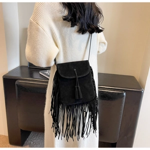 Gros plan d'un sac bandoulière en daim noir avec de longues franges et détails de glands