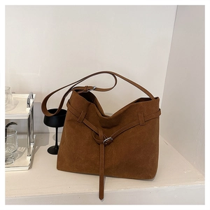 Close-up of a dark brown suede tote bag with slim shoulder straps and metallic hardware