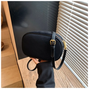 Detail of vintage matte black oval crossbody bag featuring gold hardware and leather strap