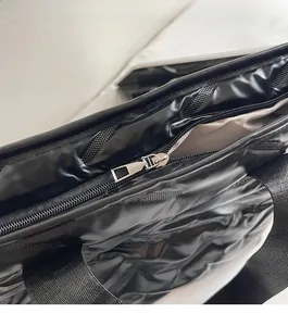 Close-up of smooth silver metal zipper and black glossy fabric on tote shoulder bag