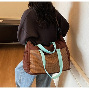 Detail of a large brown tote with blue trim and checkerboard pocket on a model