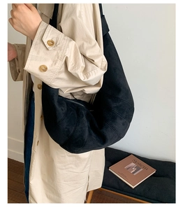 Close-up of black quilted dumpling bag on a model showing the matte suede texture