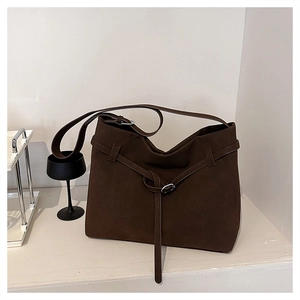 Close-up of matte dark brown suede tote bag with decorative strap and silver metal buckle