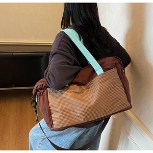 Detailed back view of a brown nylon tote bag with blue strap and checkered pocket