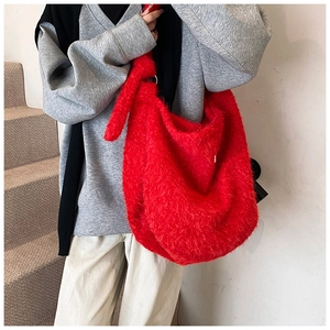 Detailed shot of large red fuzzy hobo tote bag featuring a decorative knot on the shoulder strap