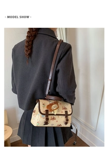 Détail d'un sac bandoulière beige imprimé chiens avec bordures brunes et charme d'ours