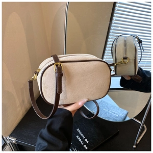 Detail of beige suede crossbody bag with brown leather trim and retro gold hardware