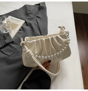 Detail of cream pleated shoulder bag with pearl chain and glossy leather texture