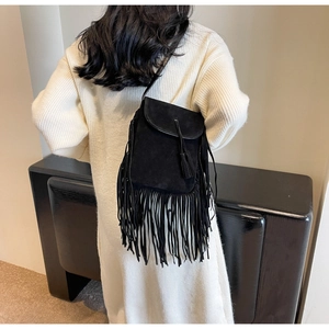 Détail du sac bandoulière bohème en daim noir avec franges sur une robe en tricot