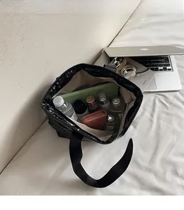 Spacious interior of black quilted tote bag holding a bottle, wallet and cosmetics