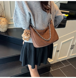Detail of brown suede hobo bag with silver chain strap and plush puppy charm