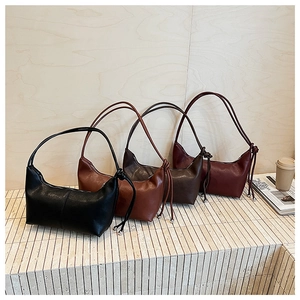 Detailed view of four minimalist faux leather crescent bags in classic autumn colors