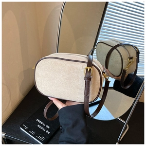 Close-up of matte crossbody bag with contrast leather trim and golden metal strap buckle