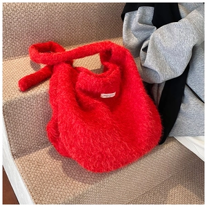 Gros plan détaillé du sac cabas en peluche rouge avec étiquette de marque sur tapis