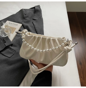 Close-up of off-white ruched cloud bag with elegant pearl handle and knotted strap