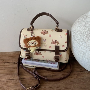 Détail du sac vintage beige avec motifs chiens et charm d'ours en peluche brun