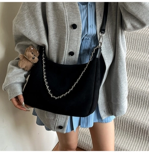 Detail of black suede crescent bag with silver chain and cute brown bear charm