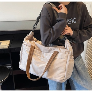 Detail of a large beige mesh tote bag with adjustable shoulder straps and brown handles