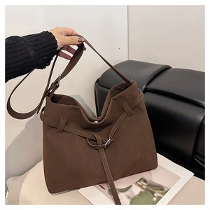 Close-up of dark brown matte tote bag with decorative tie detail and adjustable strap
