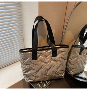 Detailed view of silver quilted tote bag with black straps and herringbone stitching