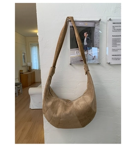 Detail of tan suede croissant bag featuring stitched panels and knotted shoulder strap