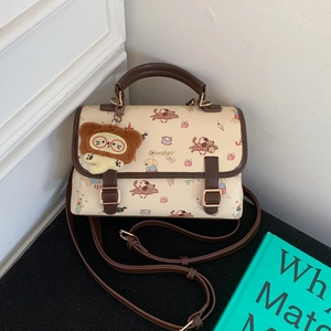 Détail du sac à main crème avec imprimé chiot de cirque et charm lion en peluche