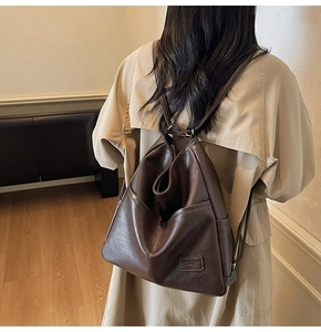 Rear view of model wearing a vintage dark brown leather backpack with minimal label