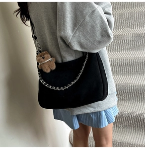 Detail of black suede hobo bag with silver chain and cute teddy bear charm