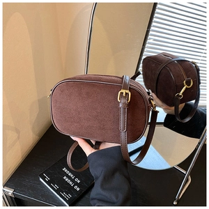Close-up of retro brown suede crossbody camera bag with vintage gold metal buckles