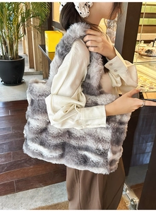 Détail du grand sac cabas en fausse fourrure à rayures grises porté à l'épaule