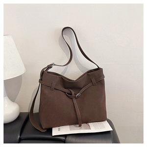Detail of dark brown matte leather tote bag with decorative cross-straps and metal rings