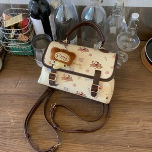 Détail du sac crème avec imprimé chiot et breloque ours en peluche sur table en bois