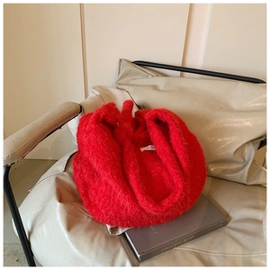 Détail du sac fourre-tout rouge en peluche sur fauteuil beige avec décor de livre chic
