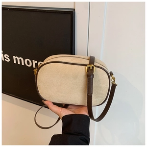 Detailed close-up of beige frosted crossbody bag with brown leather trim and gold hardware