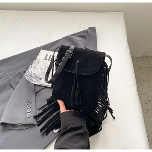 Vue détaillée du sac à bandoulière en daim noir avec franges sur fond minimaliste