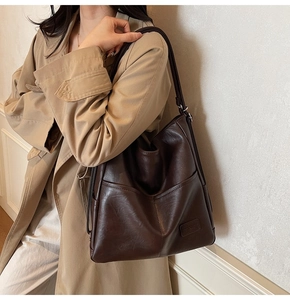 Detail view of deep brown large tote bag with visible leather texture and side logo patch