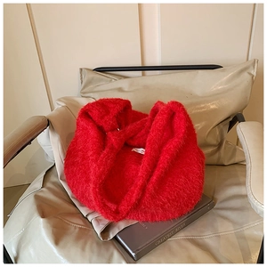 Détail du sac cabas en maille pelucheuse rouge vif sur un canapé en cuir élégant