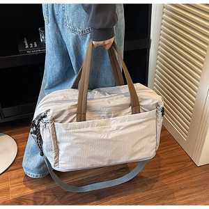 Macro shot of quilted grey travel tote bag with brown handles in minimalist home setting